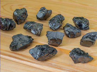 Shiny black mineral chunks displayed on a wooden surface.