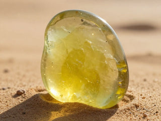 Translucent yellow stone resting on sunlit sand.