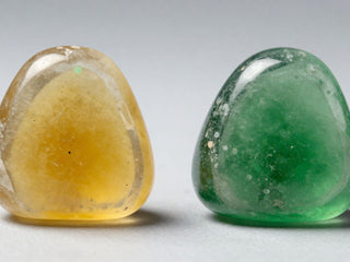 Yellow and green polished stones displayed side by side on a light background.