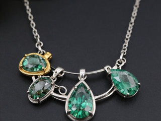 Necklace with four green gemstone pendants on silver and gold settings.